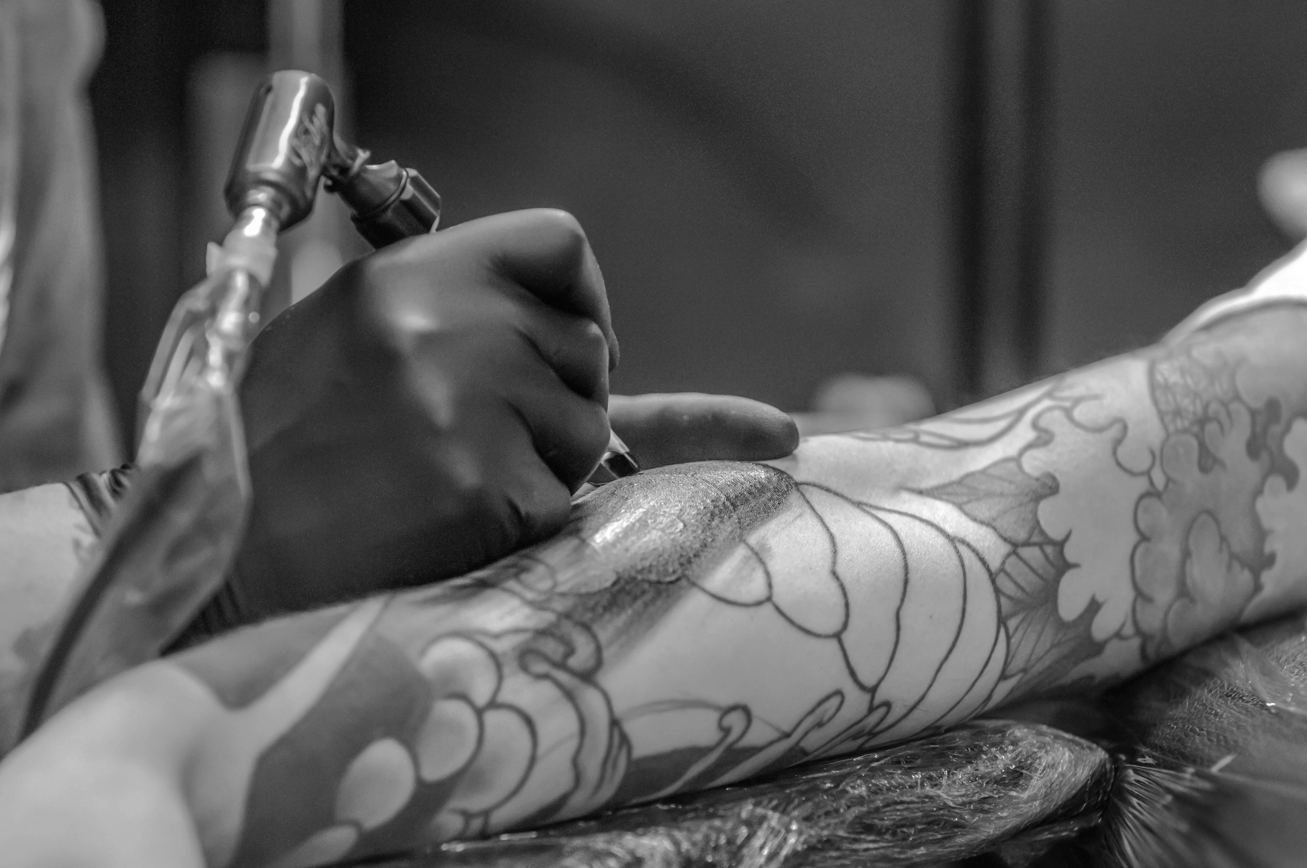 tatuagem floral sendo feita no braço por um tatuador