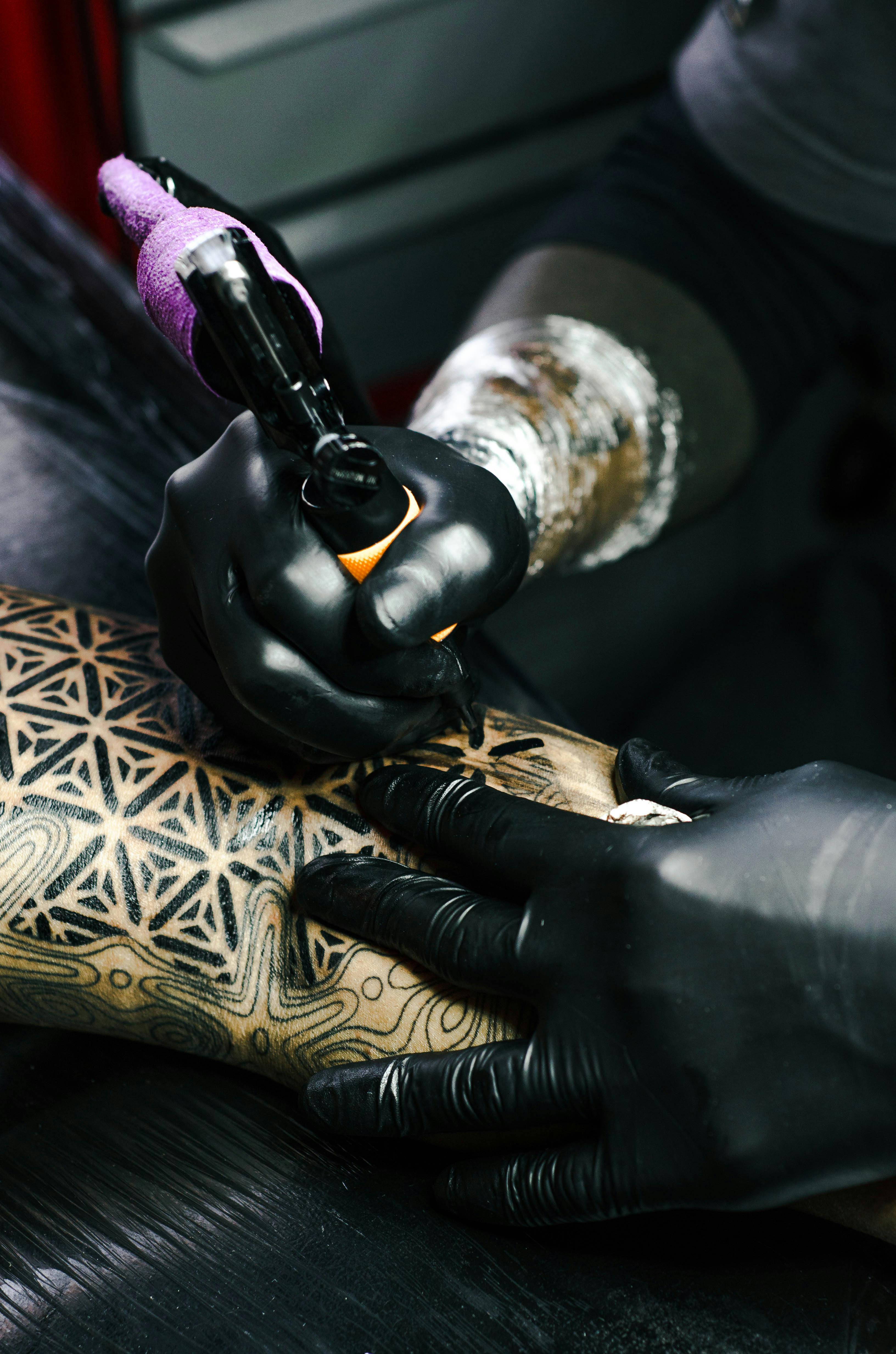 Tatuando braço de sujeito com formas geométricas.