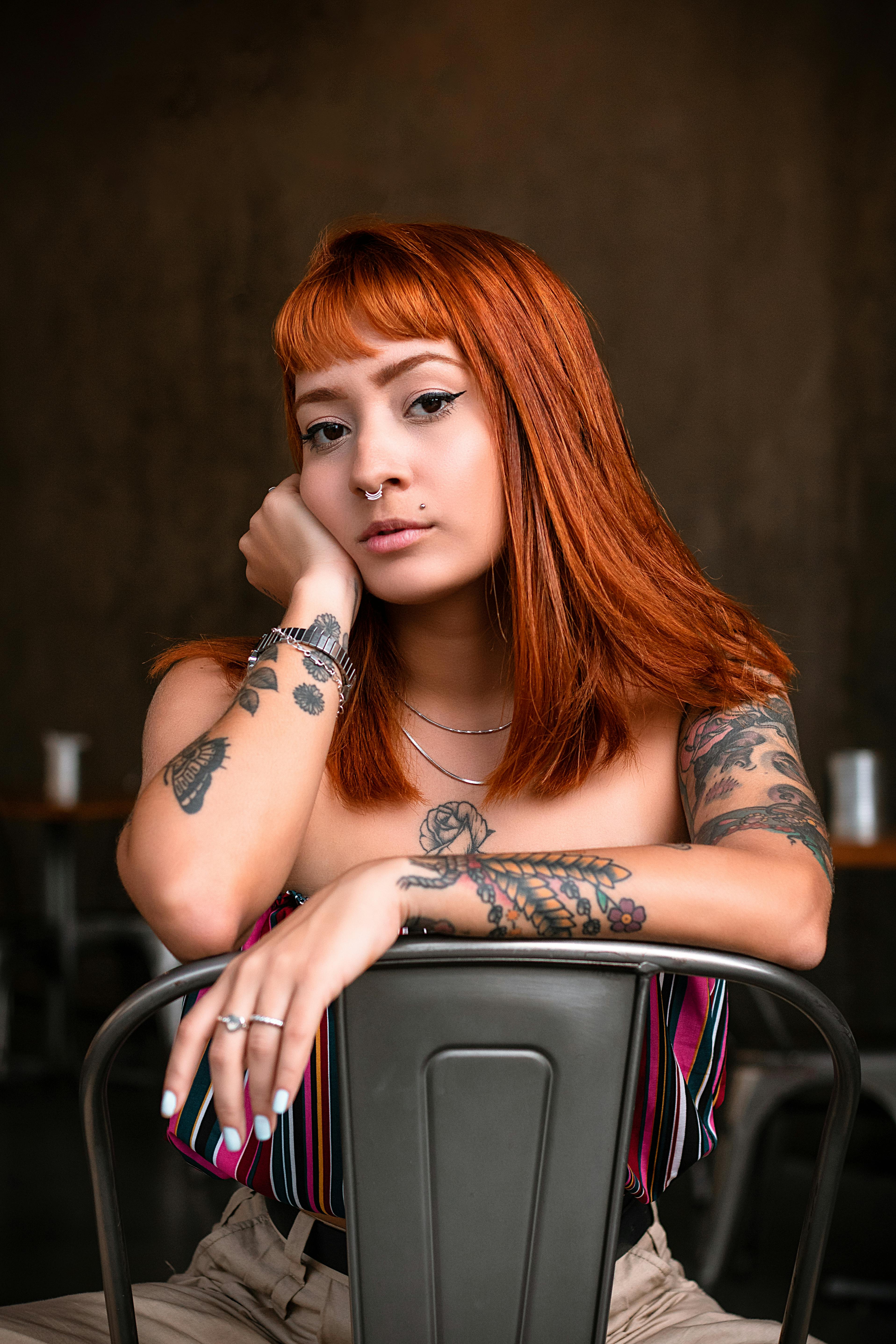 riva sentada na cadeira com os braços tatuados estilo floral.
